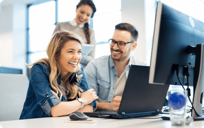 image of two coworkers laughing in front of their computers image of two coworkers laughing in front of their computers