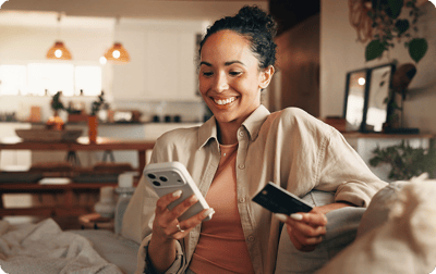 Image of women smiling at phone with a credit card in her hand Image of women smiling at phone with a credit card in her hand