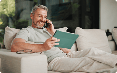 image of a man smiling at his tablet while on the phone image of a man smiling at his tablet while on the phone